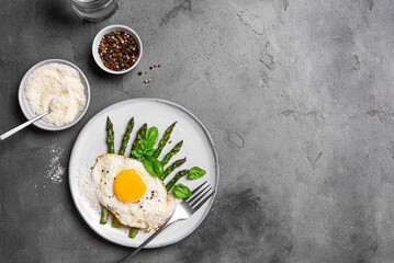 Fried egg with green asparagus and grated parmesan cheese for breakfast