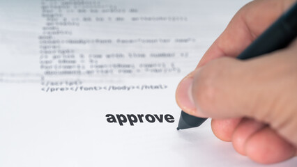 Close-up of hand writing 'approve' on a document with visible code in background, symbolizing...