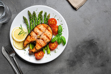 Grilled salmon steak with green asparagus, tomatoes and lemon slices
