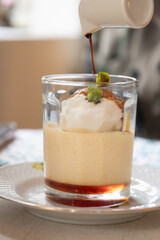 Indulgent dessert featuring creamy texture topped with ice cream and syrup, elegantly presented in a glass dish.