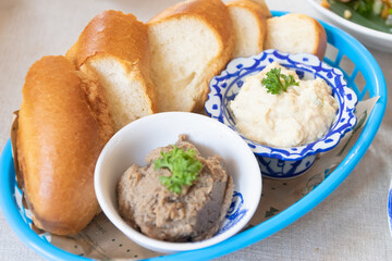 A delightful dish featuring soft bread rolls alongside creamy spreads served in traditional bowls, perfect for a gourmet experience.