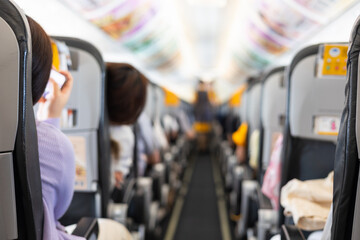 Inside commercial airplane, passengers sit calmly in economy class. Selective focus of the aisle, with blurred seats creating depth. It shows air travel, aviation lifestyle, or transportation scenes.