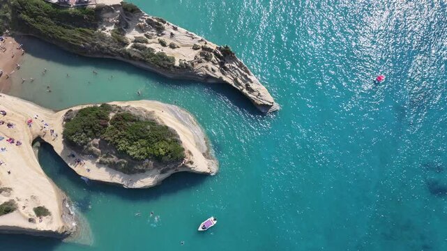 4k aerial video footage, backwards flying from Kanali tou Erota beach at Sidari coastline in north part of Corfu Island, with Sidari cityscape, sandstone cliffs and mountain landscape in background