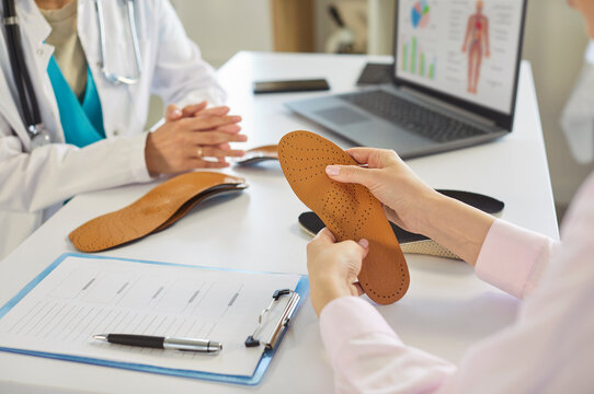 Patients hands holding leather orthopedic insole with pattern at orthopedists office for examination, custom insets for foot pain relief, comfortable walk. Shoe improvement, orthotic product concept
