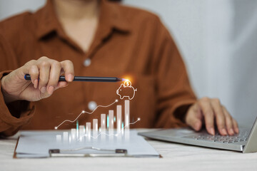 A person at a desk with a laptop points to a digital graph showing savings growth leading to a...