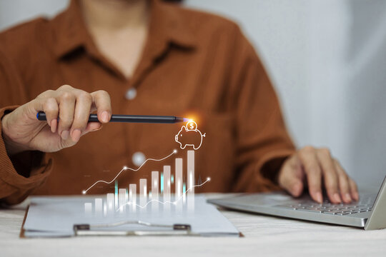 A person at a desk with a laptop points to a digital graph showing savings growth leading to a piggy bank, symbolizing financial planning.