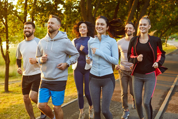 Positive runners team engages in running during group training outdoors, promoting sport, fostering...