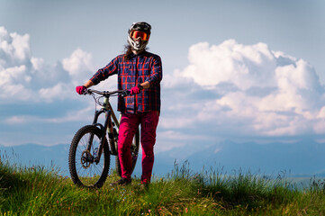 Unrecognizable athlete in protective gear standing in a field and looking at the camera against the...