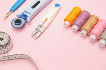 Colorful Sewing Threads and Tailor Tools on Pink Background