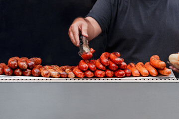 Vendor Grills And Stacks Juicy Sausages At Food Stall