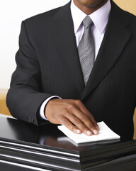 Person in suit gently polishes tomb with cloth, reflecting sense of care and respect