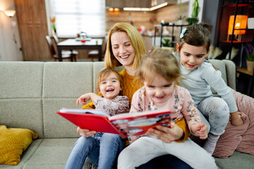 Mother looks at a book and reads a story to her daughters