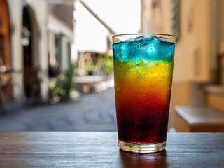 A refreshing Italian soda with rainbow layers served in a clear glass in a café scene