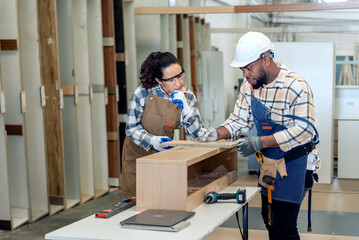 Two colleague young aged carpenter standing aim equipment tool for wood furniture at wood plank in...