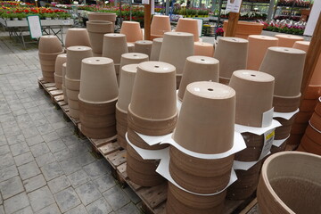 Many terracotta flower pots stacked on wooden pallets in garden center