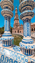 Symmetrical composition of decorative ceramics in blue with the tower of the Plaza de España in Seville in the background, one of the most important architectural icons of the Andalusian city.
