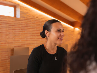 A woman pays attention to what a coworker says, during a colloquium talk in the office