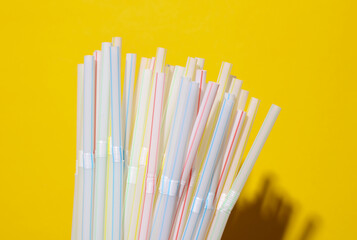 Set of plastic straws on yellow background
