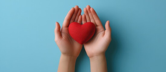 Hands cradling a red plush heart against a calming turquoise background