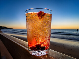 Italian soda drinks with strawberries and lemon photographed in front of beach sunsets
