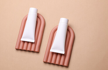Geometric line podiums with white cream tubes on beige background. Creative beauty showcase. Top view. Minimalistic mockup for design