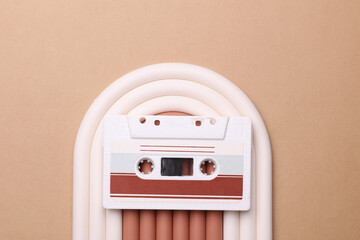 Geometric line podium with retro audio cassette on beige background.