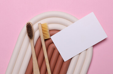 Geometric line podium with wooden toothbrushes and white business card on pink background. Creative...