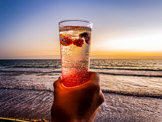 Italian soda drinks with strawberries and citrus photographed at the beach during sunset