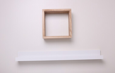 Square wooden and photo frame shelves on white wall