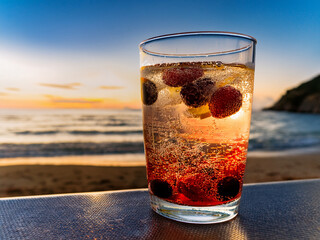 Italian soda drinks with strawberries and citrus photographed at the beach during sunset