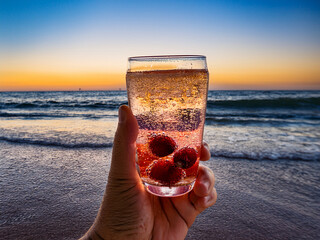 Italian soda drinks with strawberries and citrus photographed at the beach during sunset