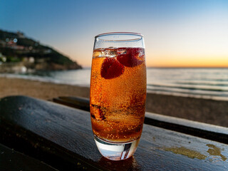 Italian soda drinks with strawberries and citrus photographed at the beach during sunset