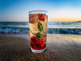 Italian soda drinks with strawberries and citrus photographed at the beach during sunset