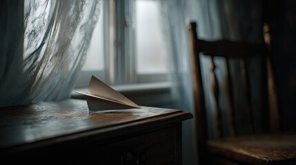 Paper airplane on an antique table by a window. Soft light streams through sheer curtains