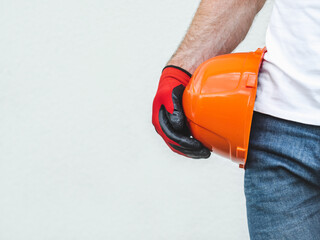 Attractive man, orange hard hat and protective gloves. Labor day. Front view, close up, studio shot. Labor and employment concept