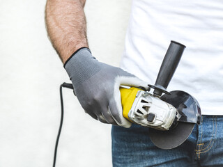 Attractive man, angle grinder and work clothes. Labor day. Front view, close up, studio shot. Labor and employment concept