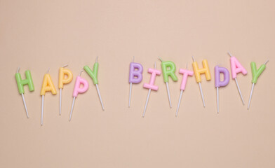 Happy birthday letter shaped candles on beige background