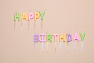 Happy birthday letter shaped candles on beige background