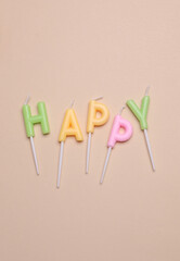 Happy birthday letter shaped candles on beige background