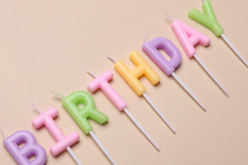 Happy birthday letter shaped candles on beige background