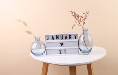 Lightbox calendar with date january 21 and vases with dry flowers on table