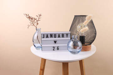 Lightbox calendar with date january 26 and vase with dry flower, lamp on table