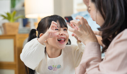 Asian daughter playing to be a ghost while playing happily with her mother, who joins in the fun. A...