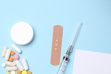 White card and Pills bottle with Medical Adhesive bandage plasters, syringe on blue background. Top...