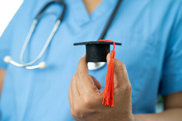 Asian doctor holding graduation gap hat, education medicine.