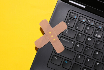 Restoration, repair of digital equipment. Laptop with medical plasters on a yellow background