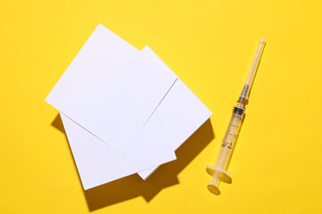 Syringe and white memo cards on yellow backgroundpo