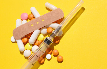 Pills with Medical Adhesive bandage plasters, syringe on yellow background. Top view
