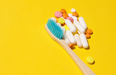 Toothbrush and pills on a yellow background