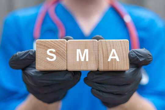 Physician holding wooden cubes with acronym: SMA. Genetic Disease SMA Diagnosis. Spinal Muscular Atrophy (SMA) Innovative Medicine and Modern Genetics Concept.